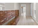 Inviting hallway with a unique brick accent wall, tile flooring, and views into the bright, neutral interior at 14010 102Nd Ave, Largo, FL 33774