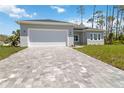 View of the gray brick driveway leading to a well-maintained gray house with a two car garage at 4344 Jaslo Ave, North Port, FL 34286