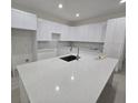 Close up of white kitchen island with sink and quartz countertops and ample cabinet space at 4146 New Milford St, North Port, FL 34288