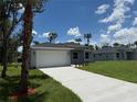 A charming house with a well-manicured lawn and a long drive, complemented by tropical palms and blue sky at 4098 New Milford St, North Port, FL 34288
