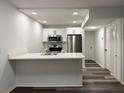 Modern kitchen features white cabinets, stainless steel appliances, quartz counters, and wood-look floors at 1799 N Highland Ave # 143, Clearwater, FL 33755