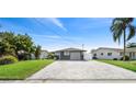 A well-maintained home with green lawn, front palm tree and driveway with gray stone pavers at 5036 Bonito Dr, New Port Richey, FL 34652
