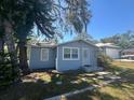 Cozy home with light blue siding and mature trees in the yard, offering a peaceful and inviting curb appeal at 8702 El Portal Dr, Tampa, FL 33604