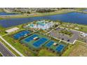Stunning aerial view of community amenities, including swimming pool, clubhouse, tennis court, and playground overlooking a lake at 6018 Jensen View Ave, Apollo Beach, FL 33572
