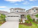 Charming two-story home with a two-car garage, lush landscaping, and a welcoming front porch at 6026 Jensen View Ave, Apollo Beach, FL 33572
