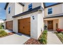 Up close exterior view of a townhome with a brown garage door, entry door and attractive landscaping at 5424 Companion Ln, Tampa, FL 33619