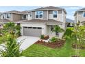 Stylish two-story home with gray siding, stone details, a gray garage door, and a landscaped front yard at 6038 Jensen View Ave, Apollo Beach, FL 33572
