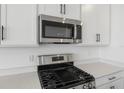 Close-up of the kitchen showcasing stainless steel microwave, gas range, white cabinets, and quartz countertops at 6046 Jensen View Ave, Apollo Beach, FL 33572