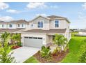 Exterior shot of a two-story home featuring a well-manicured lawn, colorful landscaping, and a two-car garage at 6058 Jensen View Ave, Apollo Beach, FL 33572
