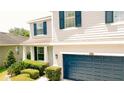 Two-story home featuring gray siding, a dark blue garage door, well-maintained landscaping, and a charming front porch at 12236 Fairlawn Dr, Riverview, FL 33579