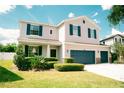 Charming two-story home with light gray siding, a three car garage, dark blue shutters and complemented by lush, green landscaping at 12236 Fairlawn Dr, Riverview, FL 33579