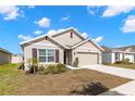 Charming single-Gathering home featuring neutral paint, a two-car garage, and a well-manicured front lawn on a sunny day at 16750 Sunburst Lake St, Wimauma, FL 33598