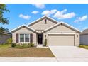 Charming single-Gathering home featuring neutral paint, a two-car garage, and a well-manicured front lawn on a sunny day at 16750 Sunburst Lake St, Wimauma, FL 33598