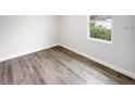 An empty bedroom offers wood look floors and a window overlooking the outdoors at 17381 Tyler Ave, Port Charlotte, FL 33948