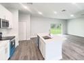 A gourmet kitchen features stainless appliances, a large island with sink, and wood look floors at 17381 Tyler Ave, Port Charlotte, FL 33948