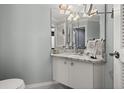Well-lit bathroom featuring a granite vanity, large mirror, and coastal decor at 1103 Kensington Ct, Safety Harbor, FL 34695