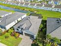 Aerial view of a home with a screened pool, manicured landscaping, and lake view at 11330 Burgundy Dr, Venice, FL 34293