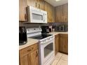 Close-up of kitchen with wood cabinets, white appliances, and ample counter space at 12322 Alta Mira St, North Port, FL 34287
