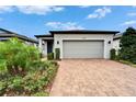 Lovely front exterior displaying brick driveway, blue front door with wreath, and green landscaping at 19165 Iron Topsail Isle, Land O Lakes, FL 34638