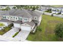 Aerial view of a two-story townhome featuring a brick-paved driveway, a two-car garage, and a well-kept lawn at 5367 Riverwalk Preserve Dr, New Port Richey, FL 34653