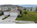Two-story townhome showcasing an attached two-car garage, brick-paved driveway, and well-manicured lawn at 5367 Riverwalk Preserve Dr, New Port Richey, FL 34653