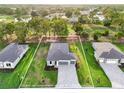 Aerial view of a one-story home with well-kept landscaping, a gray roof, and a gray brick driveway at 9127 Players Dr, Weeki Wachee, FL 34613