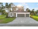 Beautiful single-story home with a gray brick driveway, stone accents, manicured lawn, and a two-car garage at 9127 Players Dr, Weeki Wachee, FL 34613