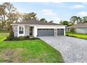 Beautiful single-story home with a gray brick driveway, stone accents, manicured lawn, and a two-car garage at 9127 Players Dr, Weeki Wachee, FL 34613