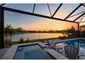 Screened-in pool and hot tub with a beautiful sunset and water view, ideal for relaxing evenings at 14553 Eagle Branch Dr, Nokomis, FL 34275
