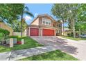 Spacious brick driveway with a two-car garage and well-maintained lawn with mature trees at 6932 Gray Catbird Loop, Wesley Chapel, FL 33545