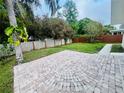 Expansive backyard featuring a circular brick patio and lush greenery, perfect for outdoor relaxation at 801 Leeward Way, Palm Harbor, FL 34685