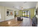 Cozy living room with sliding glass doors to backyard, wood-look floors, and a modern ceiling fan at 4502 Banyan Tree Pl, Riverview, FL 33578