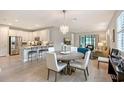 Open-concept dining area with a round table and modern chandelier, flowing into the kitchen and living room at 17109 Kenton Ter, Bradenton, FL 34202