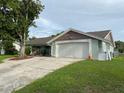 View of a single-story house showing the front yard with a long driveway and green grass at 12215 Cobble Stone Dr, Hudson, FL 34667