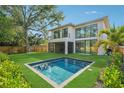 The backyard has a modern pool, green lawn, and a stylish contemporary house at 1630 Douglas Ave, Dunedin, FL 34698