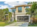 Contemporary home with clean lines, lush landscaping, and a modern glass garage door at 1630 Douglas Ave, Dunedin, FL 34698