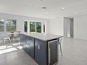 Open kitchen featuring a large island with a wine cooler, a dining table, and terrazzo floors at 15810 2Nd E St, Redington Beach, FL 33708