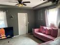 Living room featuring a pink sofa, large TV, and ceiling fan at 36940 Howard Ave, Dade City, FL 33525