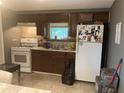 Kitchen with dark wood cabinets, white appliances, and tile flooring at 36940 Howard Ave, Dade City, FL 33525