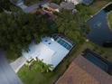 Aerial view of home with screened-in pool, mature trees, and nearby pond with fountain at 4787 Hamlets Grove Dr, Sarasota, FL 34235