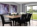 Modern dining room with a wood table, gray chairs, and view of the backyard at 22075 Blazing Star Run, Land O Lakes, FL 34637