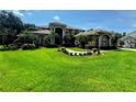 An expansive lawn and walkway lead to an elegant home nestled amongst lush green landscaping and mature trees at 5016 Givendale Ln, Tampa, FL 33647