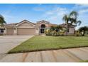 Tan house with three car garage, manicured lawn, and palm trees at 10301 Manta Way, Tampa, FL 33615