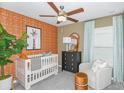 Bedroom with crib, armchair, and orange patterned wallpaper at 11222 Linden Depot Rd, San Antonio, FL 33576