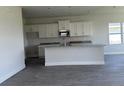 Open-concept kitchen featuring an island with granite countertops and white cabinetry at 7002 162Nd E Pl, Parrish, FL 34219