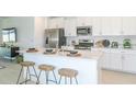 Modern kitchen with island, white cabinets, and stainless steel appliances at 2530 Leonia Ln, Zephyrhills, FL 33541