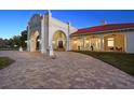 Elegant home exterior at dusk, showcasing brick pavers and arched entryway at 11623 Innfields Dr, Odessa, FL 33556