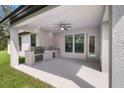 Covered patio with outdoor kitchen and ceiling fan at 17059 Nokota Ave, Hudson, FL 34667