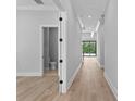 Hallway showcasing wood floors, white trim, and a view of the backyard with a sliding glass door at 3109 W Knights Ave, Tampa, FL 33611