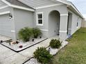 Landscaped entryway of a light gray house with an arched entry at 7855 Davie Ray Dr, Zephyrhills, FL 33540